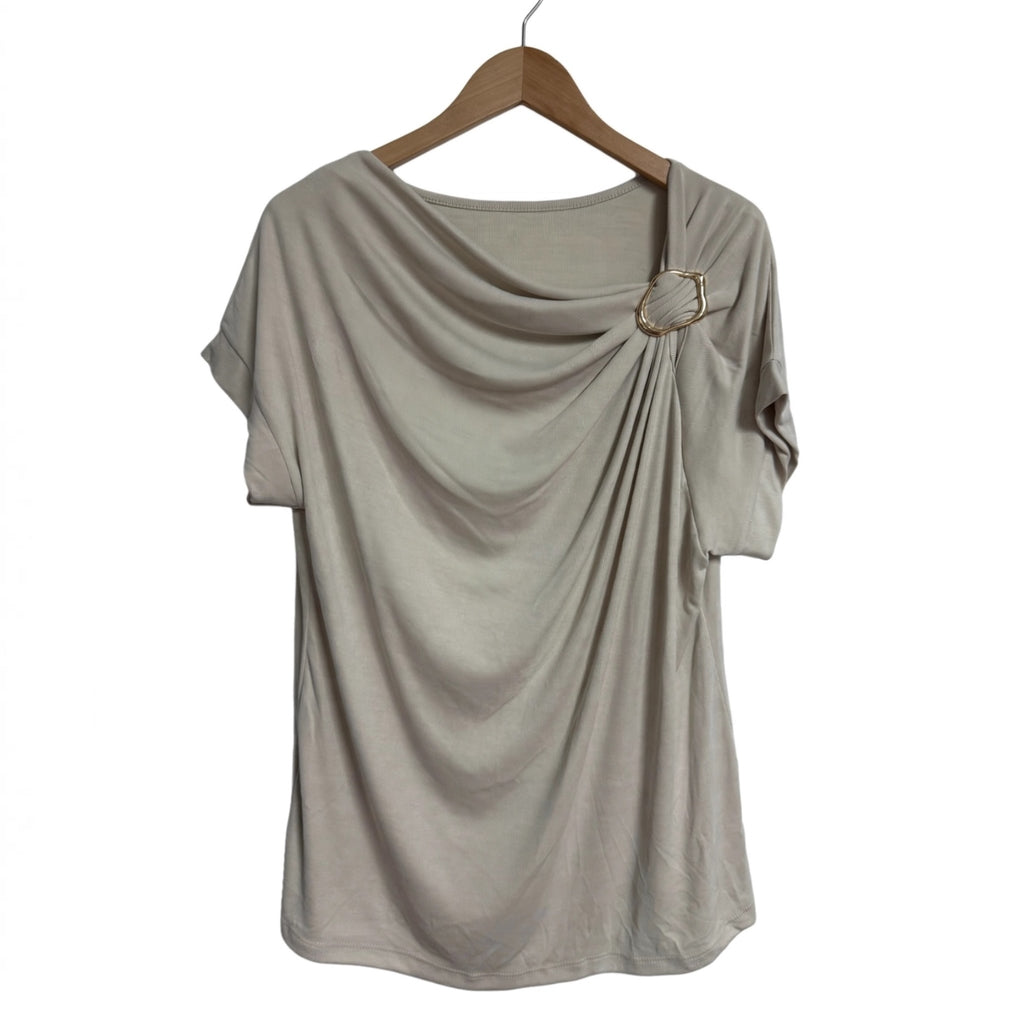 Blusa beige las cucadas de erisa con drapeado frontal, escote asimétrico y detalle de anilla metálica dorada.