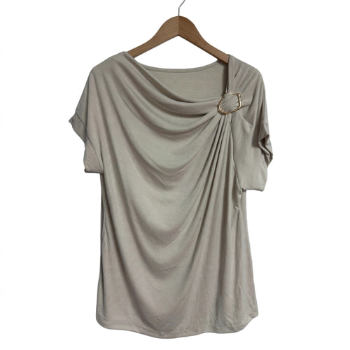 Blusa beige las cucadas de erisa con drapeado frontal, escote asimétrico y detalle de anilla metálica dorada.
