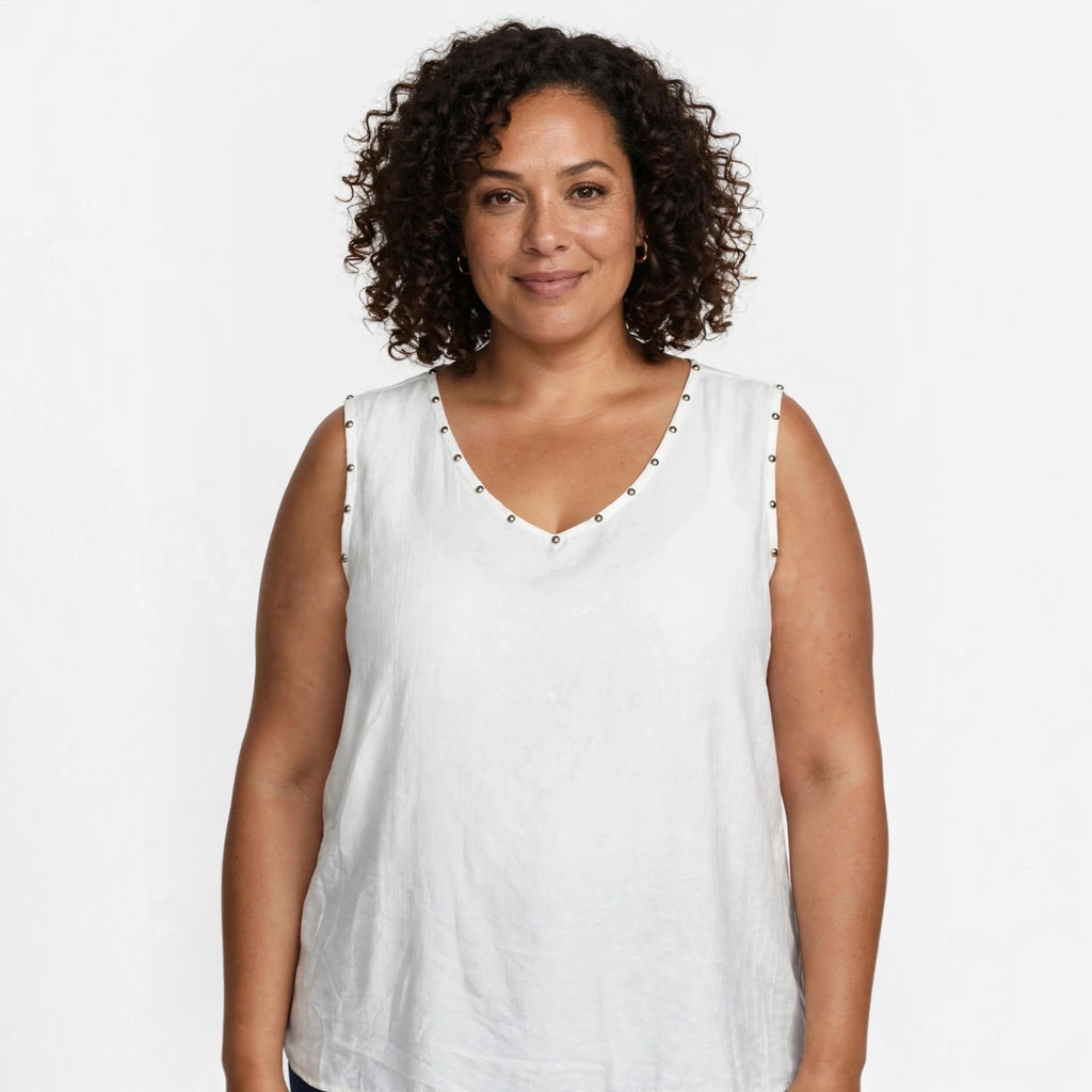 Modelo con blusa blanca sin mangas de las cucadas de erisa con detalle de tachuelas metálicas en el escote