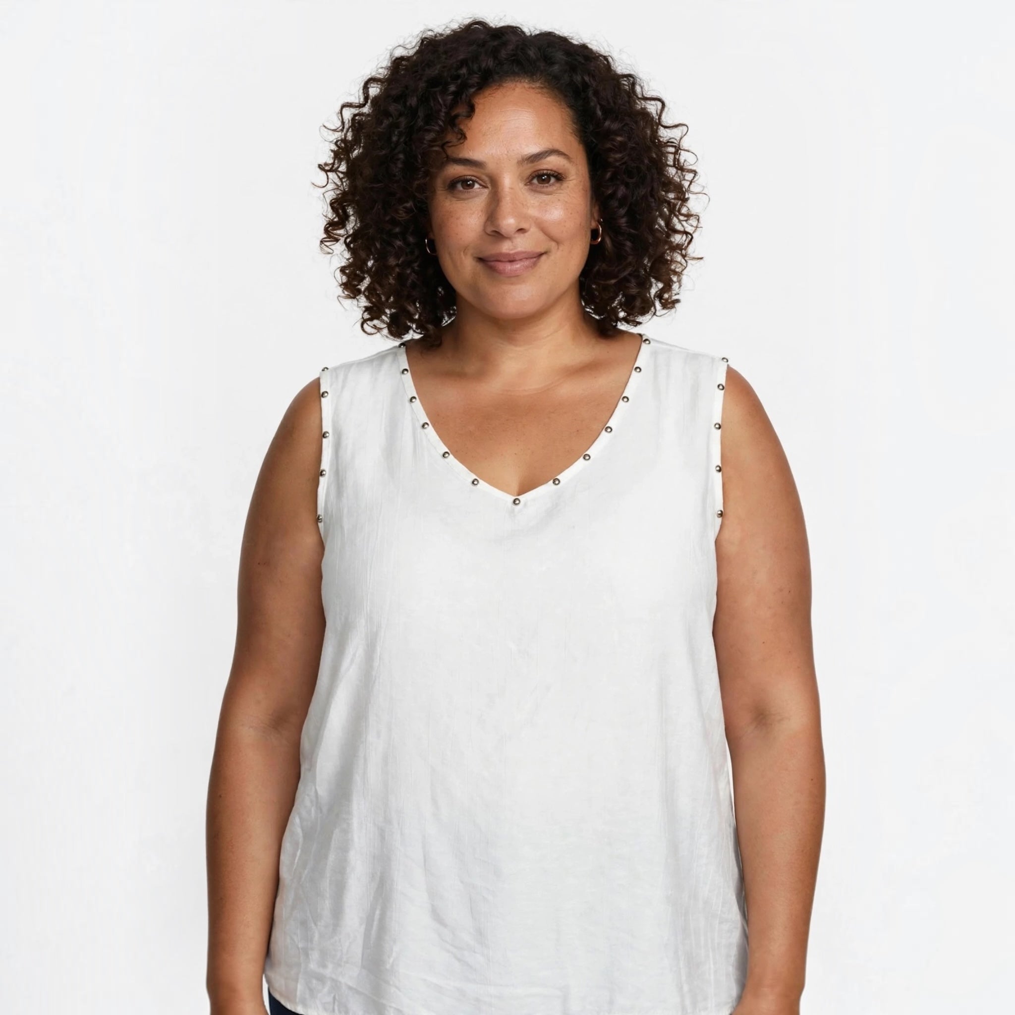 Modelo con blusa blanca sin mangas de las cucadas de erisa con detalle de tachuelas metálicas en el escote