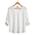 Blusa blanca las cucadas de erisa con textura arrugada, cuello en V y mangas tres cuartos ajustables con botones.