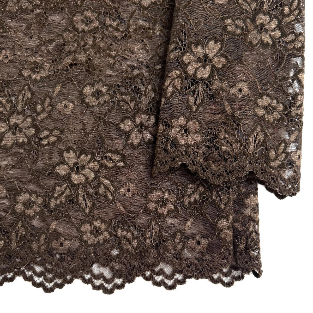 Detalle de blusa las cucadas de erisa en encaje floral marrón oscuro con bordes festoneados y textura refinada