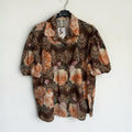 Blusa las cucadas de erisa marrón con estampado floral, cuello camisero, mangas abullonadas y detalles de encaje.