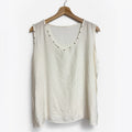 Blusa sin mangas color crema de las cucadas de erisa con detalle de tachuelas metálicas en el escote y sisas