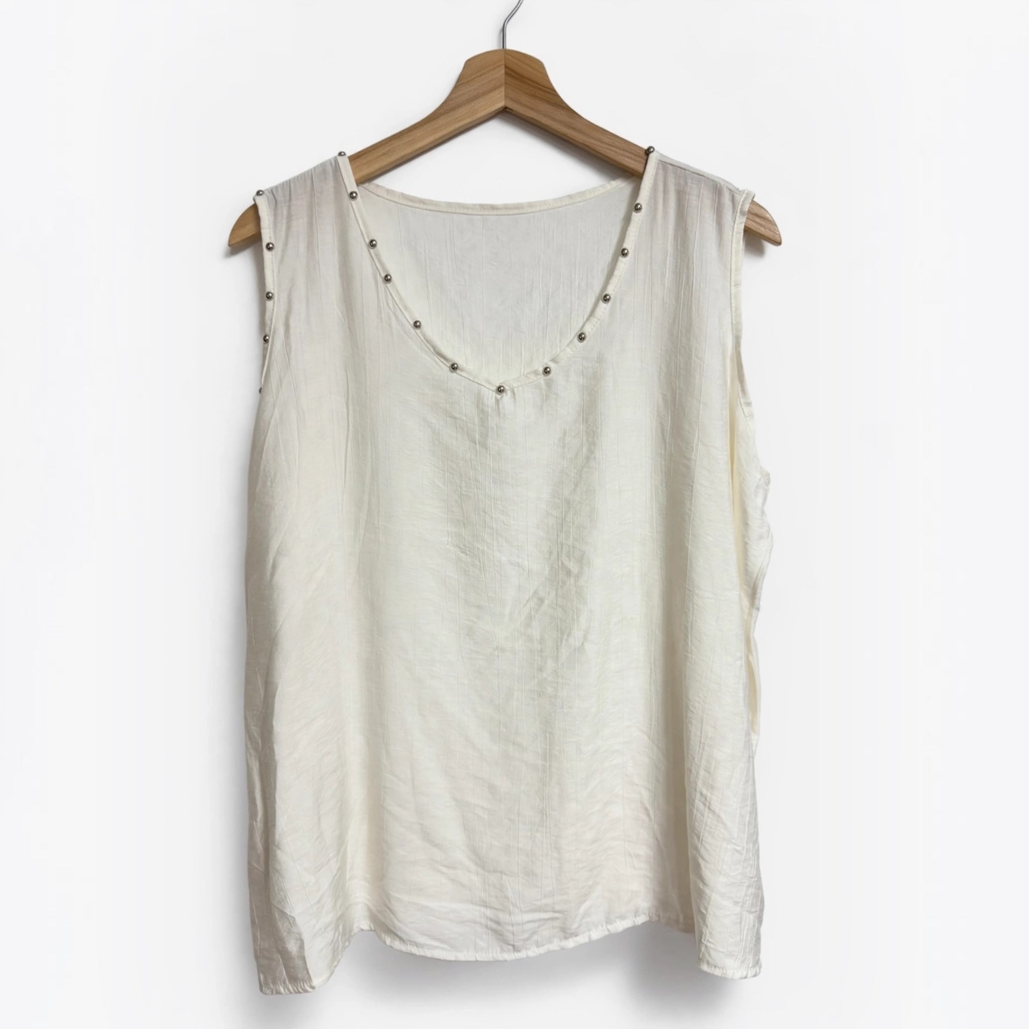 Blusa sin mangas color crema de las cucadas de erisa con detalle de tachuelas metálicas en el escote y sisas