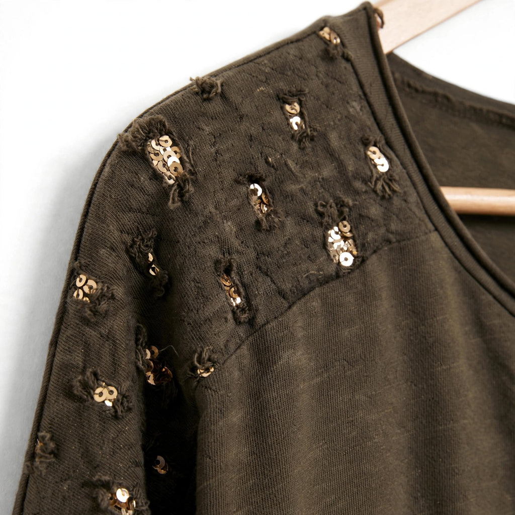 Detalle de hombro en blusa verde oliva de las cucadas de erisa con lentejuelas doradas y acabado desgastado
