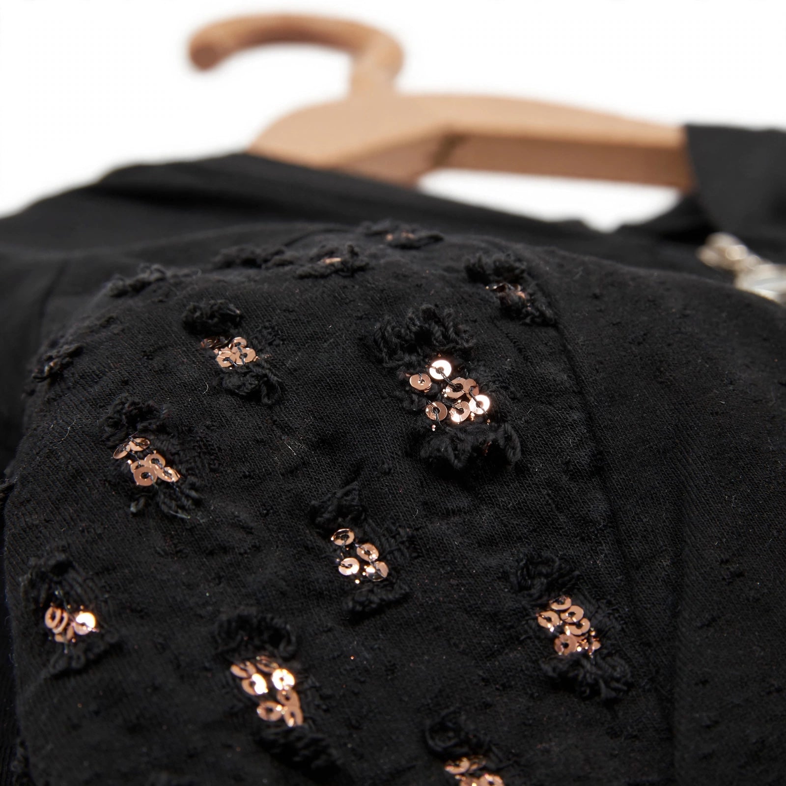 Detalle de chaqueta negra las cucadas de erisa con lentejuelas bronce y textura desgastada en hombro