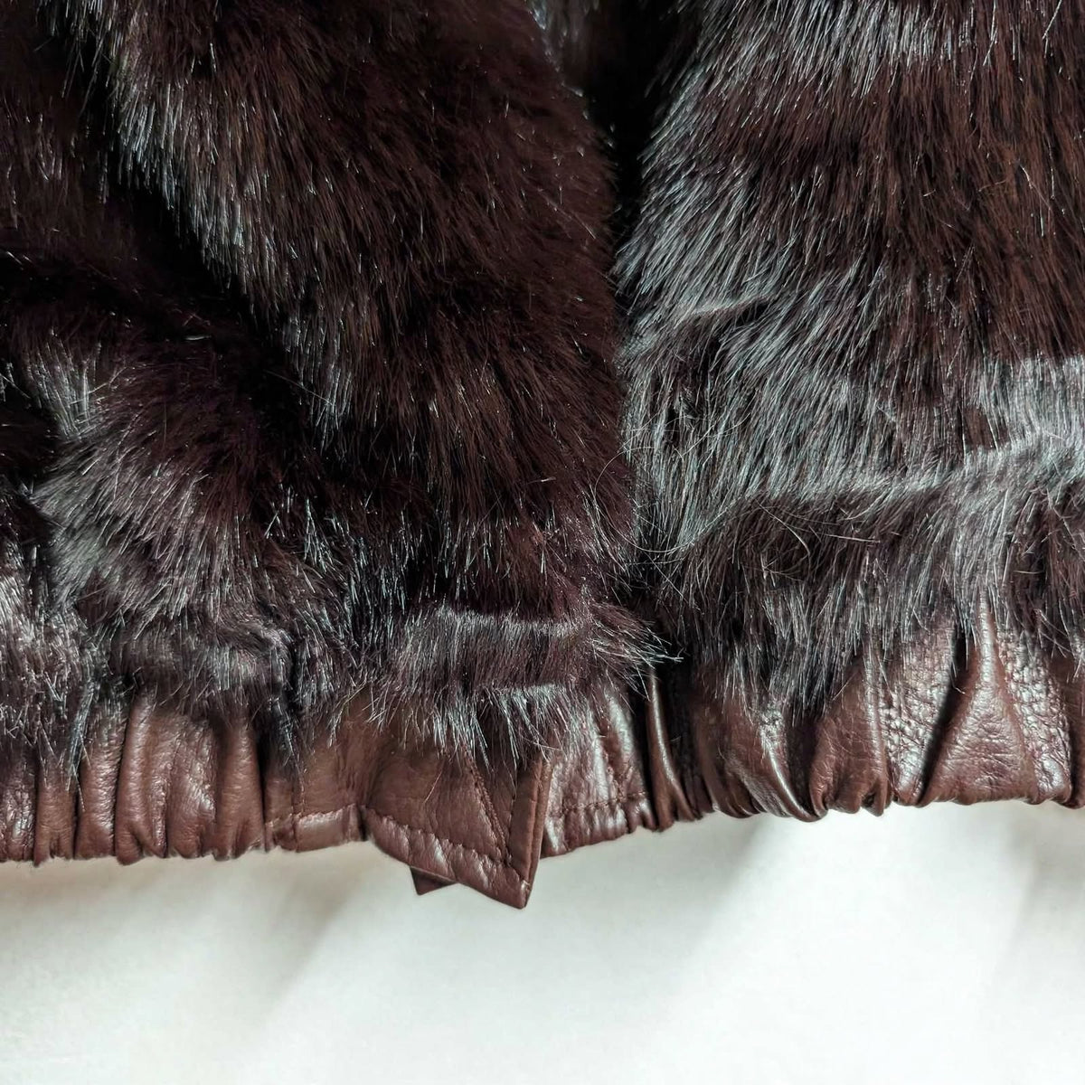 Detalle de chaqueta reversible las cucadas de erisa con pelo sintético burdeos y bajo elástico de piel sintética