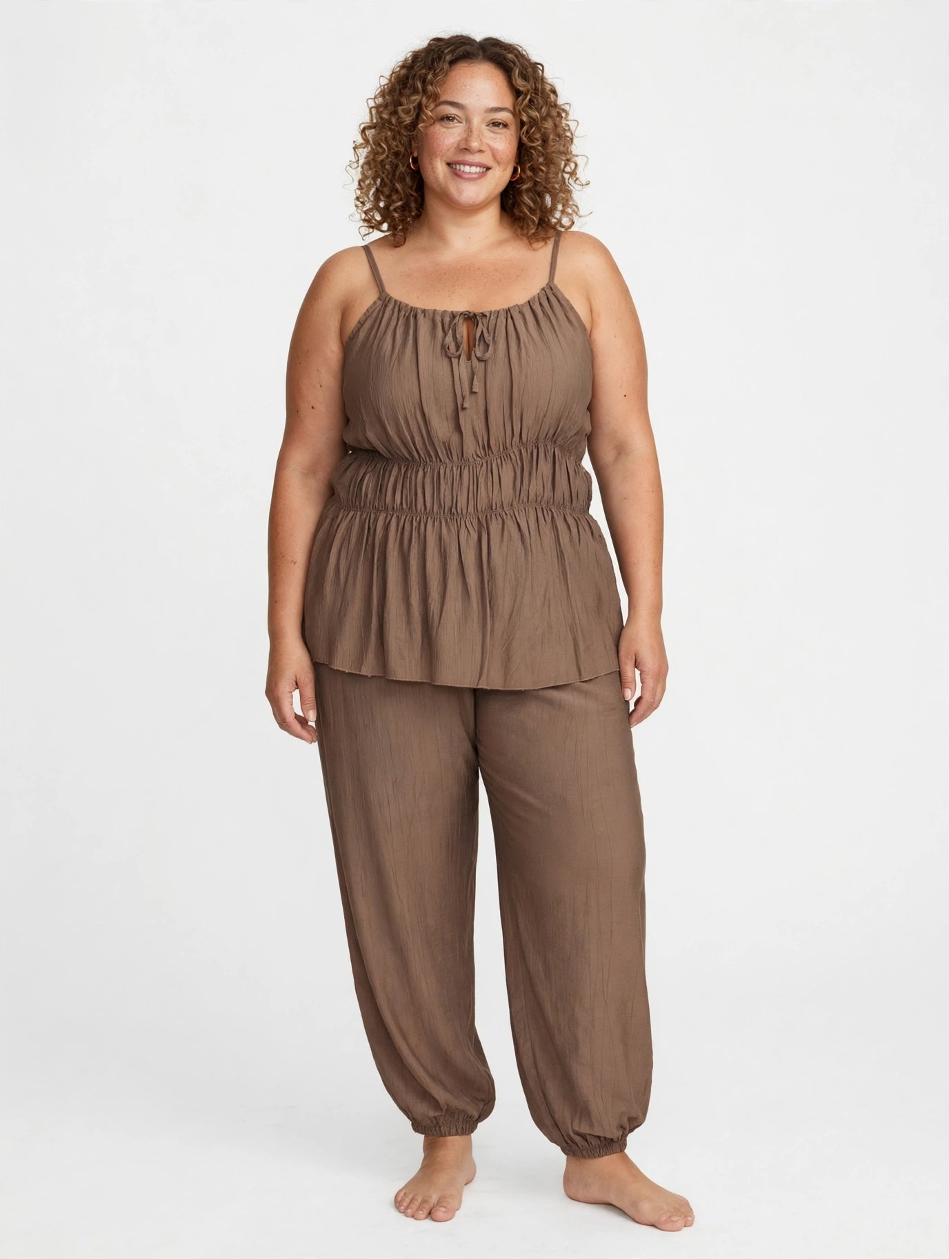 Modelo sonriente vistiendo conjunto de dos piezas marrón de las cucadas de erisa con top fruncido y pantalón holgado.
