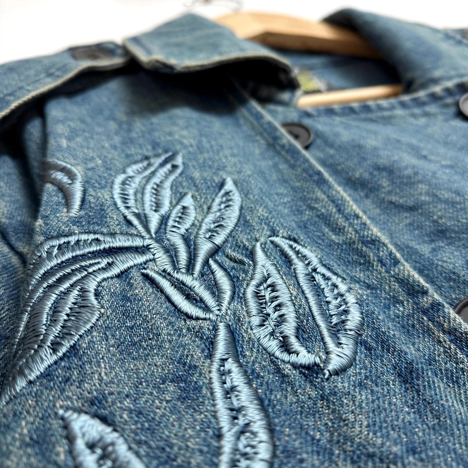Detalle de bordado floral en gabardina de mezclilla azul de las cucadas de erisa con solapa y botones