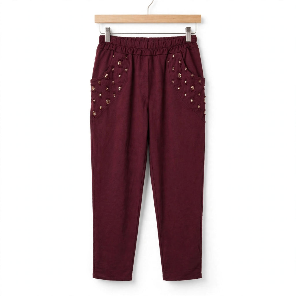 Pantalones las cucadas de erisa color burdeos con tacto ante, cintura elástica y bolsillos con lentejuelas y bordados.