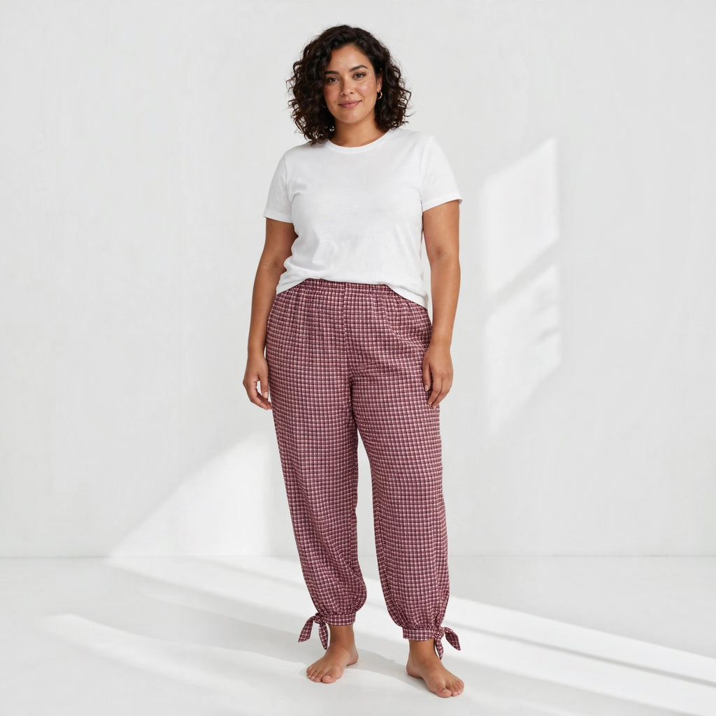 Modelo vistiendo pantalones las cucadas de erisa de cuadros granates con cintura elástica y lazos en los bajos