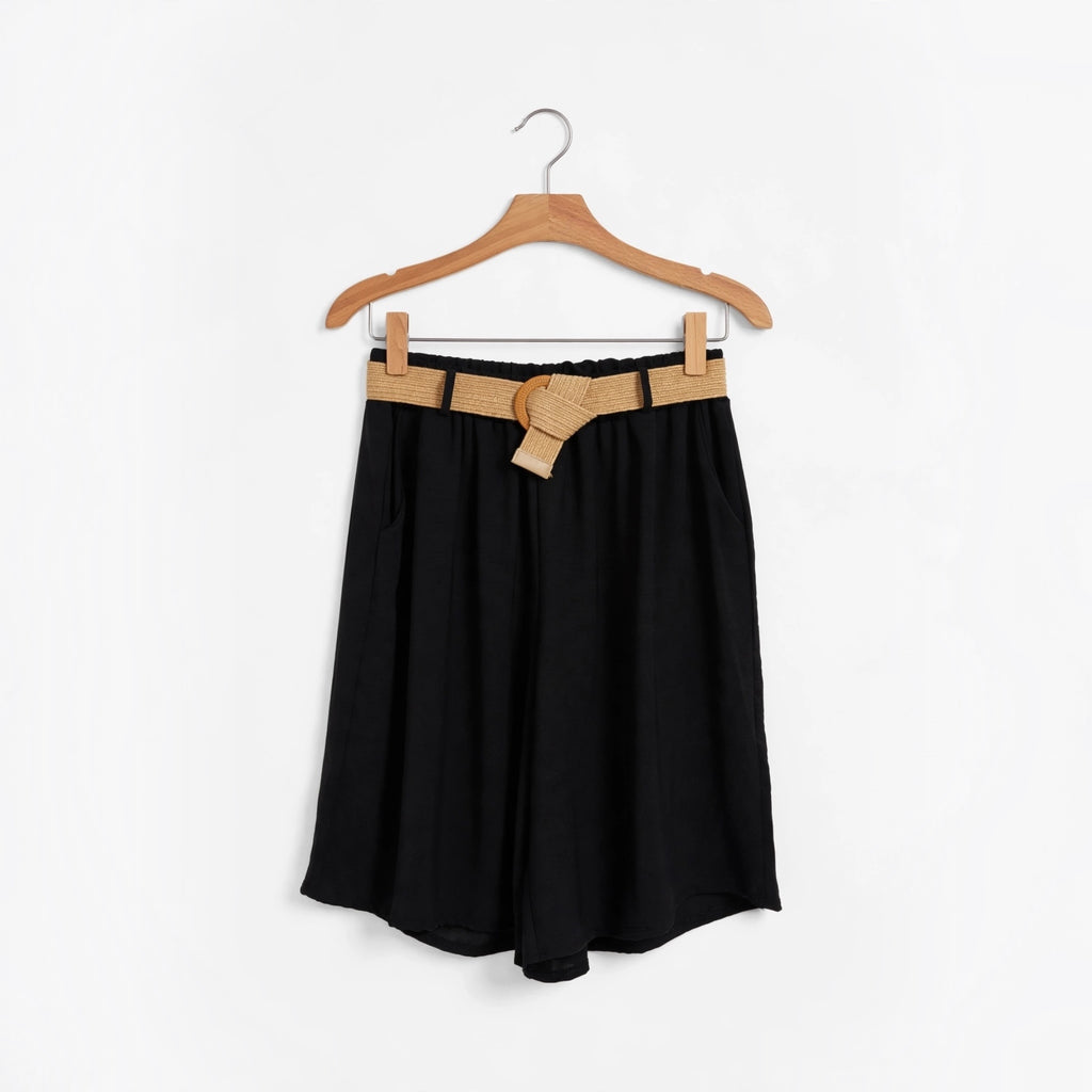 Shorts negros fluidos de las cucadas de erisa con cinturón de rafia natural y hebilla redonda en percha de madera