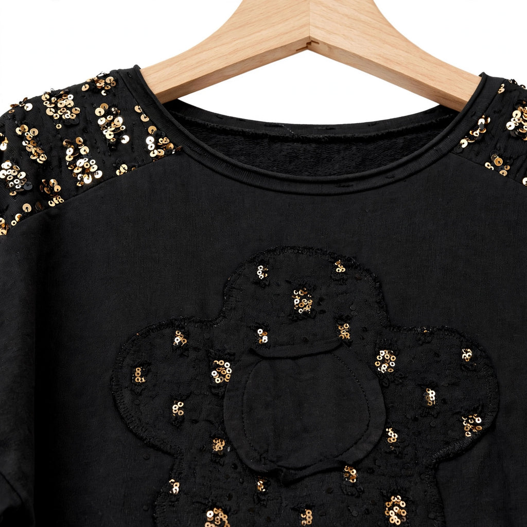 Sudadera negra las cucadas de erisa con aplique floral de lentejuelas doradas y detalles brillantes en los hombros