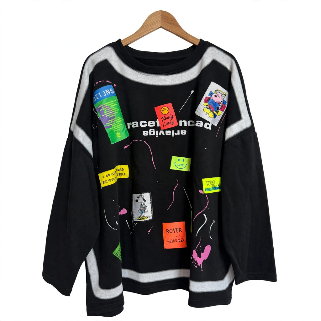 Sudadera oversize negra las cucadas de erisa con parches coloridos, salpicaduras de pintura y detalles gráficos.
