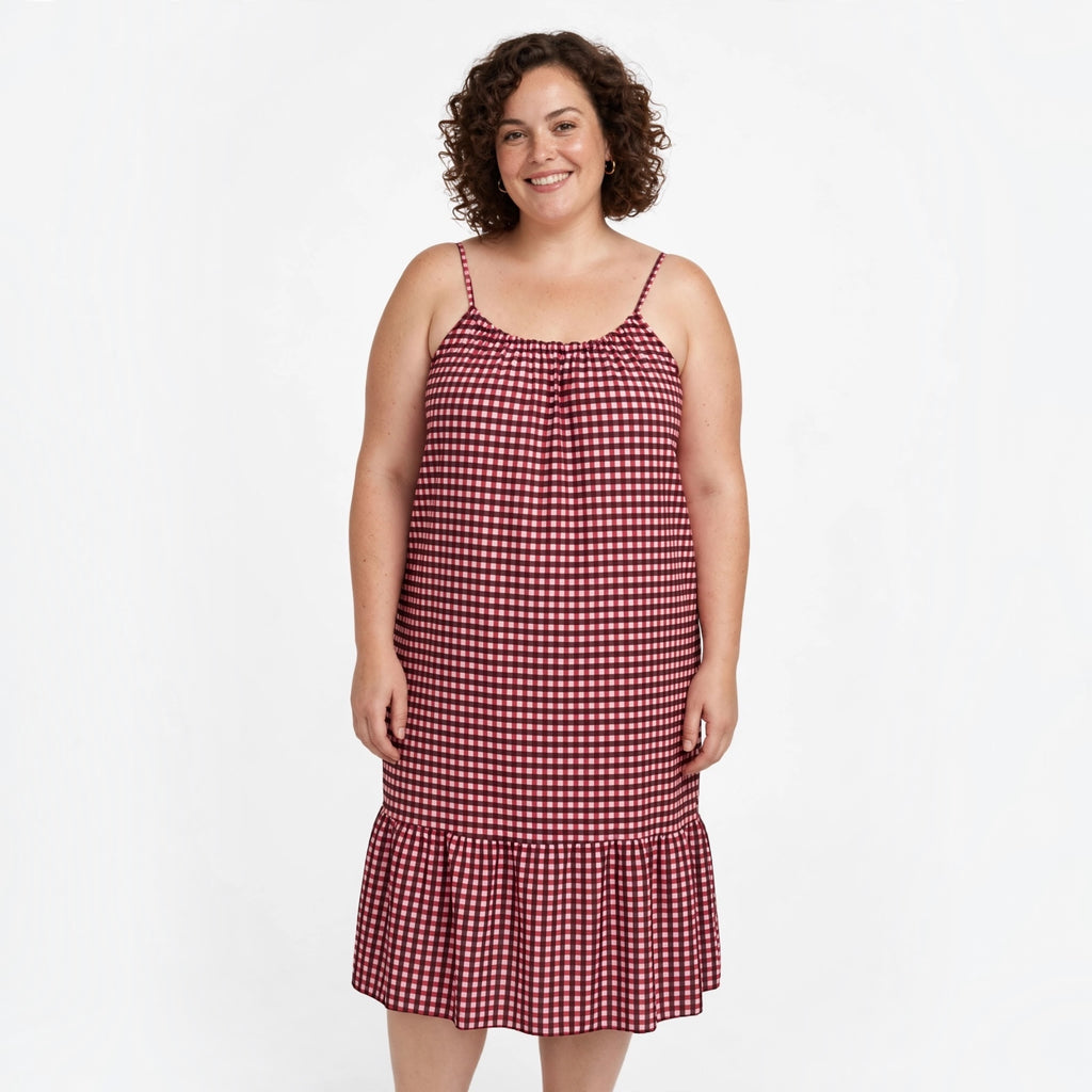 Mujer sonriente vistiendo un vestido midi las cucadas de erisa de tirantes con estampado de cuadros vichy rojo y volante