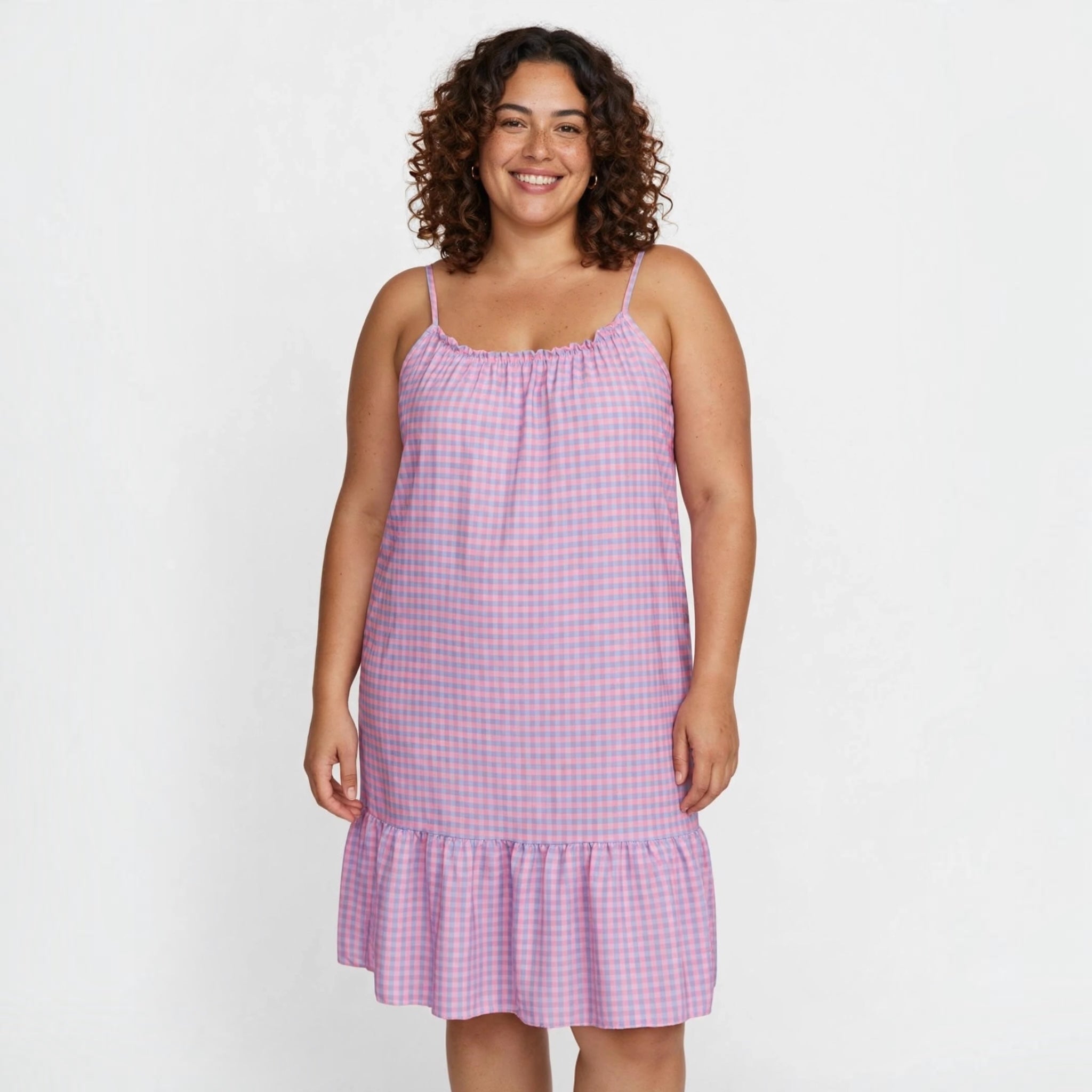 Modelo sonriente vistiendo un vestido midi de tirantes las cucadas de erisa con estampado de cuadros vichy rosa